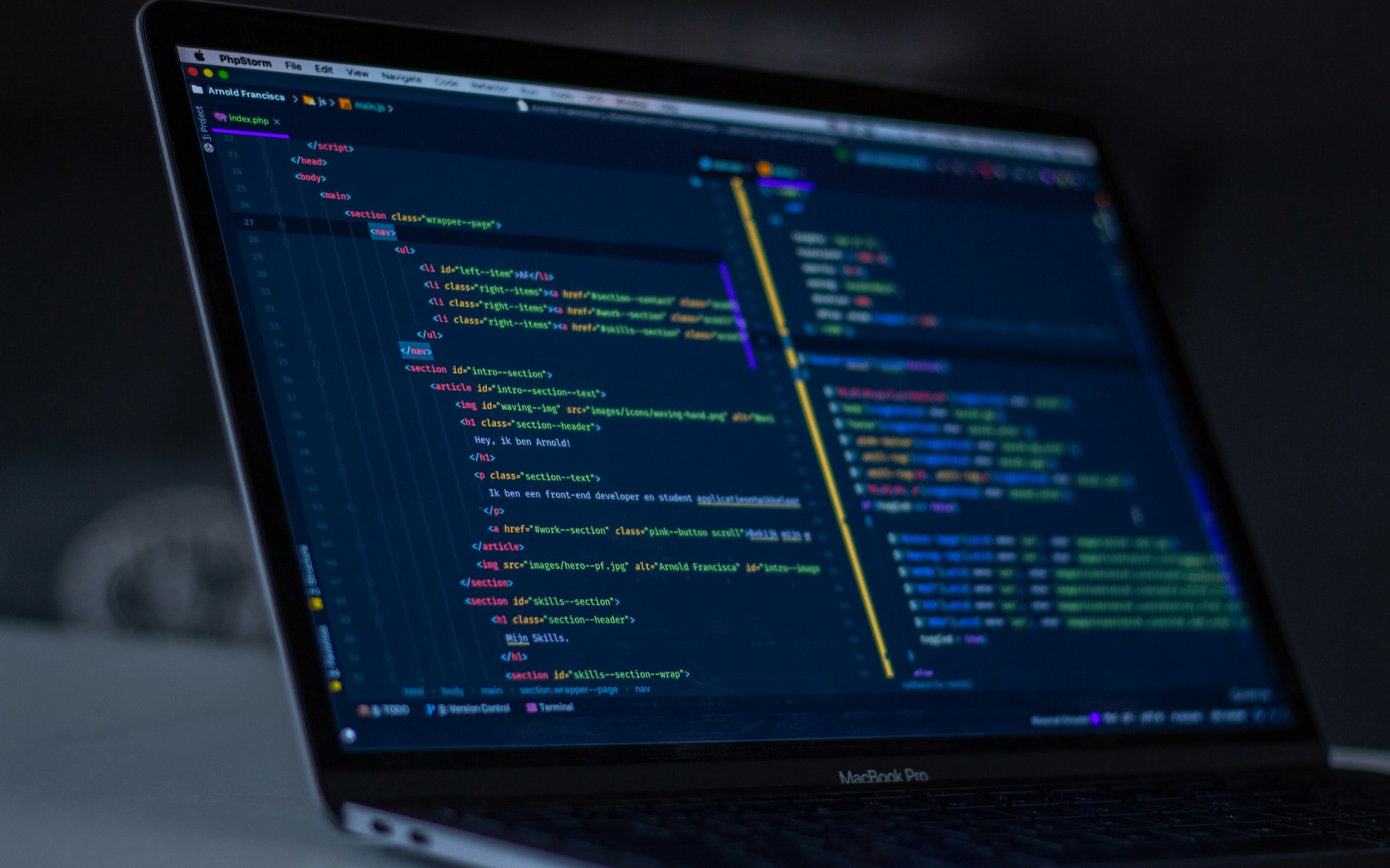 Editor de código en un portátil, con HTML y JavaScript en tema oscuro.